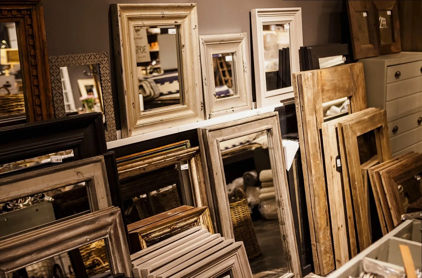 A collection of vintage-style mirror frames on display in a cozy interior shop setup.